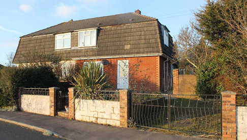 Older style home with a driveway and front garden.